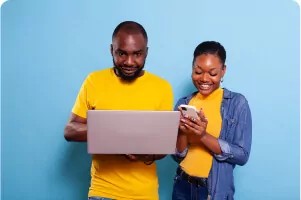 happy-man-woman-using-laptop-computer-smartphone-studio-modern-people-with-gadget-mobile-phone-browsing-internet-millennial-boyfriend-girlfriend-with-technology