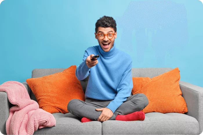 people-leisure-pastime-concept-overjoyed-unshaven-adult-man-sits-lotus-poses-sofa-holds-remote-control-watches-funny-show-television